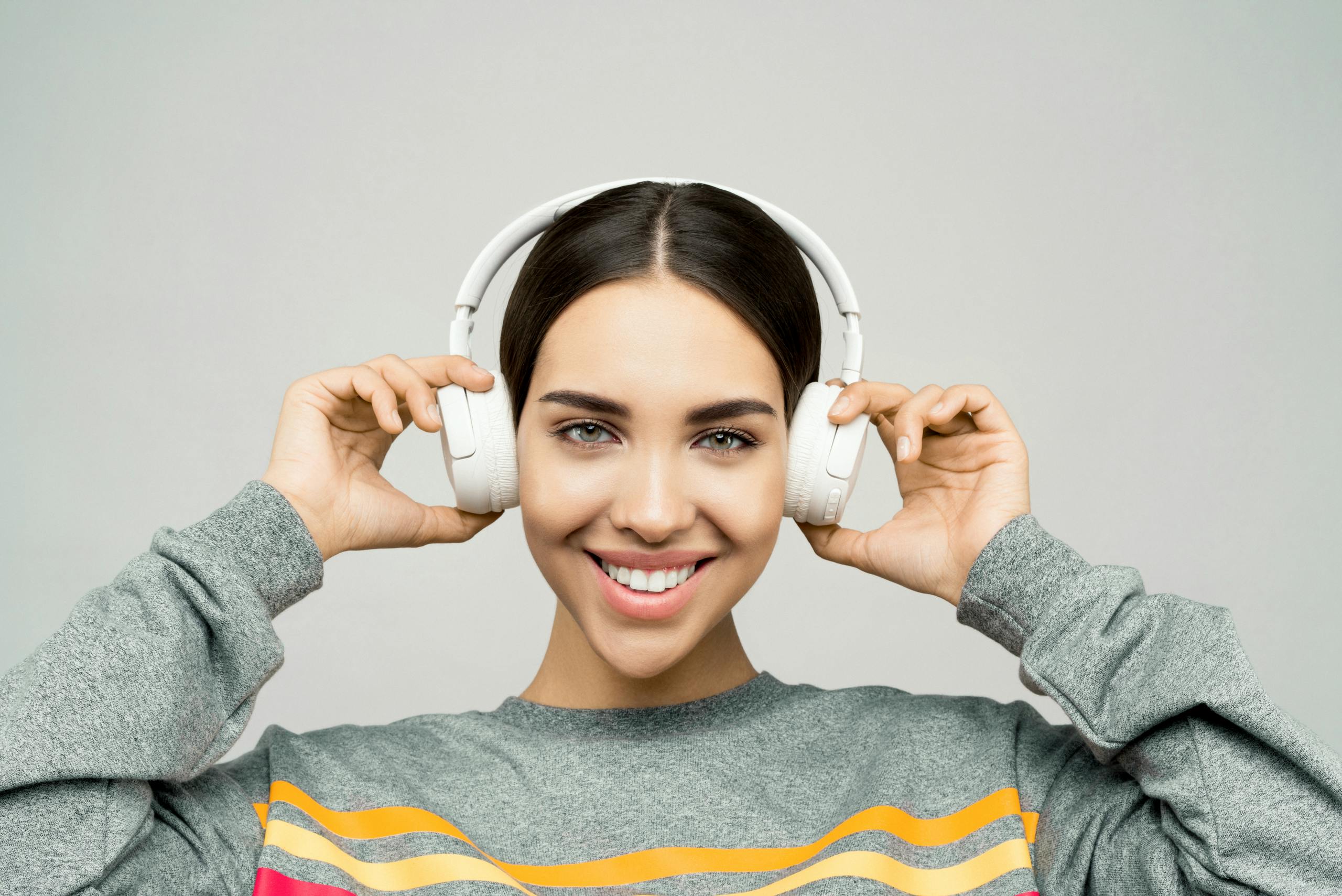 Portrait of a woman smiling while enjoying music with wireless headphones.