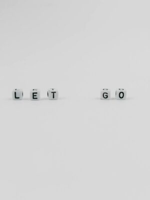 Simple white dice spelling 'LET GO' on a plain surface, conveying inspiration and motivation.