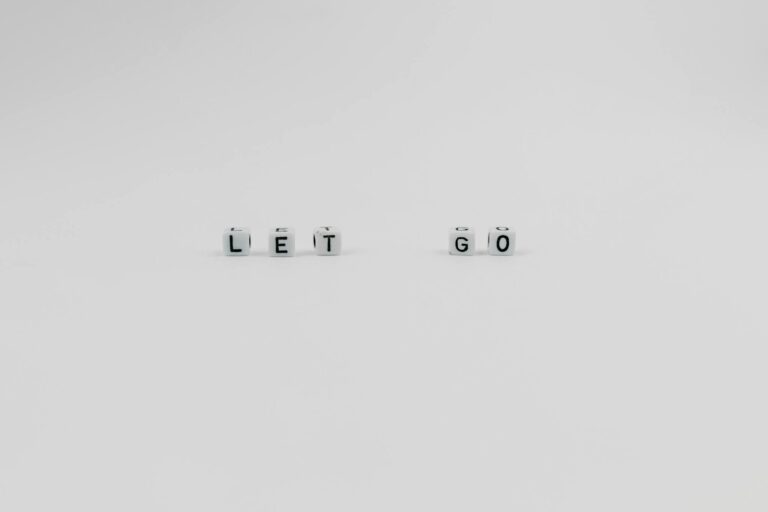 Simple white dice spelling 'LET GO' on a plain surface, conveying inspiration and motivation.