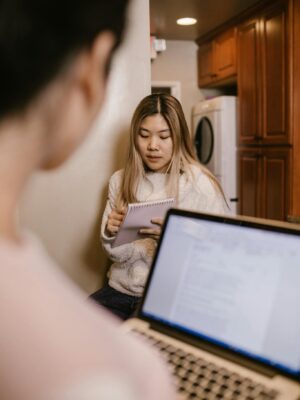 Young woman engaged in online learning at home with a laptop and notebook.